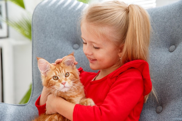 Menina sentada em uma cadeira abraça o gato