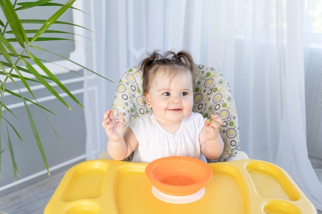 Menina sentada em uma cadeira alta e rindo do conceito de comida para bebê