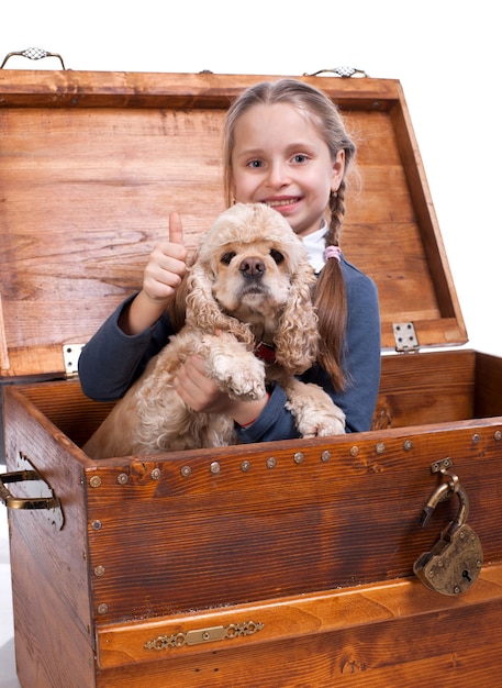 Menina sentada em uma caixa com um cachorro ang mostrando sinal de sim em um fundo branco