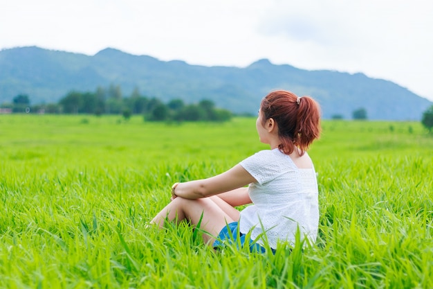 Foto menina sentada em uma grama de campo de manhã