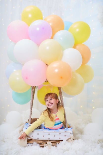 Menina sentada em uma nuvem ao lado de uma cesta de balão nas nuvens, viajando e voando com chapéu e óculos de aviador.