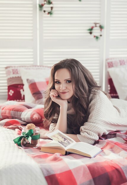 Menina sentada na cama com enfeites de Natal