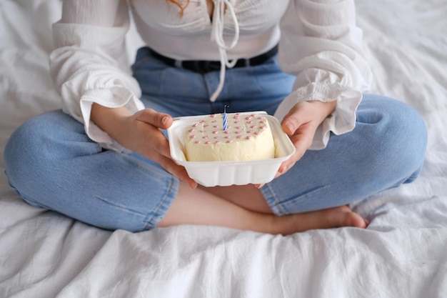 Menina sentada na cama e segurando o bolo bento no pacote para viagem