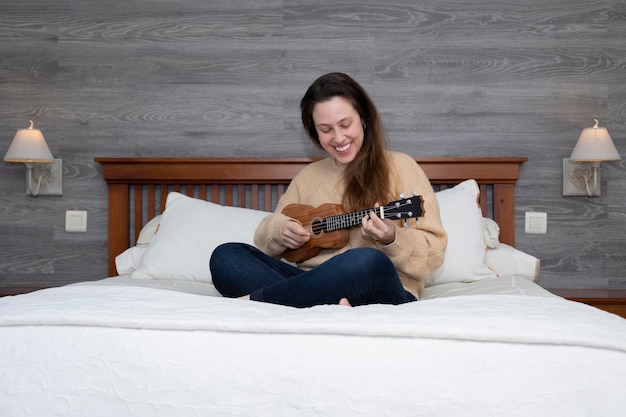 Menina sentada na cama tocando violão