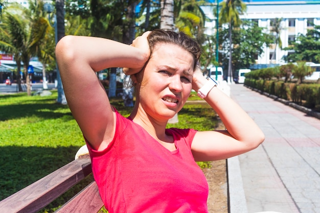 Menina sentada no banco, sofrendo de calor, mulher com insolação.