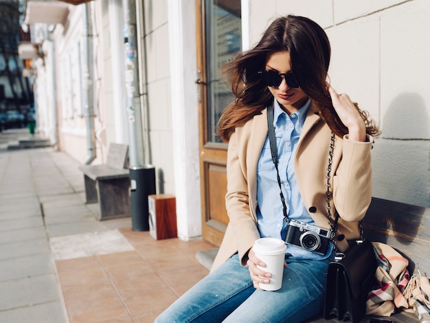 Foto menina sentada no banco tomando café