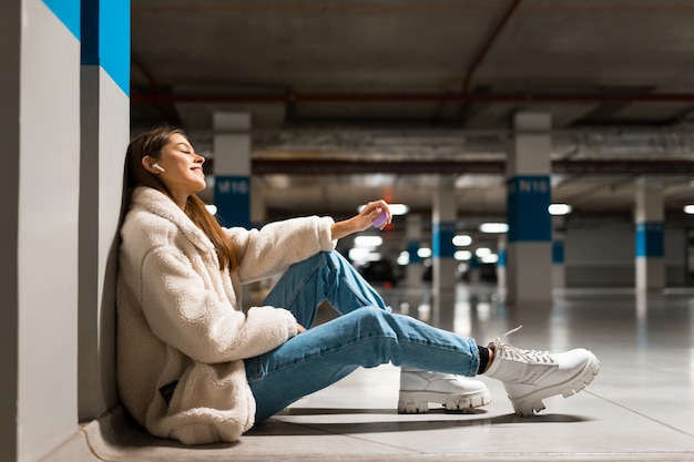 Menina sentada no chão de um estacionamento subterrâneo