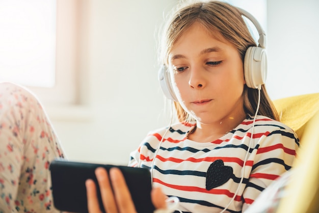 Menina sentada no sofá e usando telefone inteligente