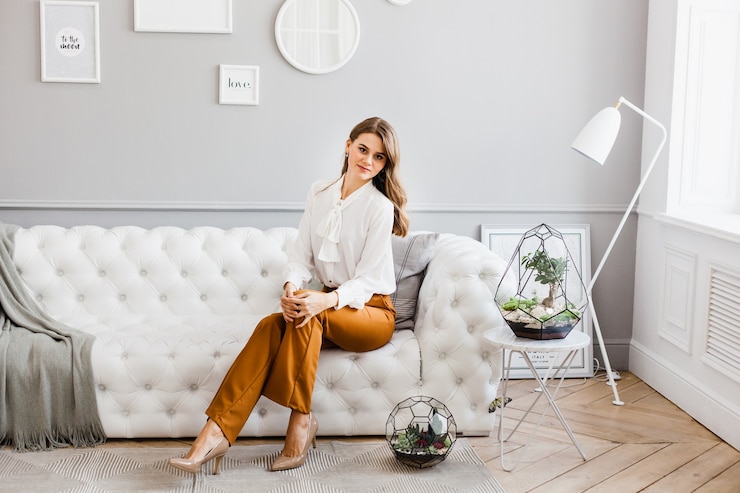 Menina sentada no sofá, interior claro, formas de plantas