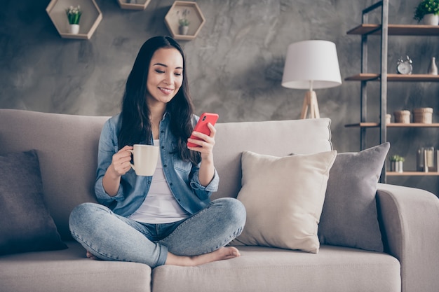 Menina sentada no sofá olhando para o telefone