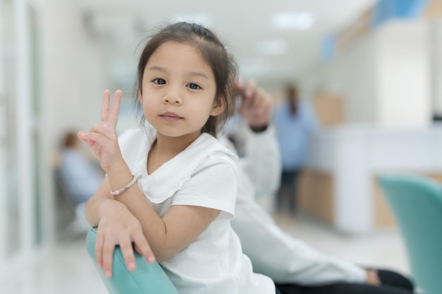 Menina sentada sorrindo no saguão do hospital