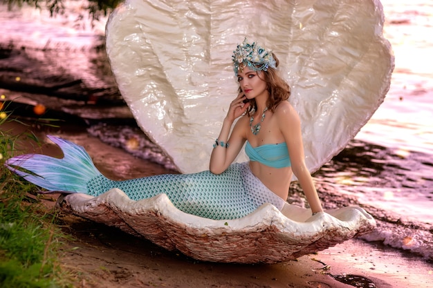 Foto menina sereia sentada perto da água ao entardecer