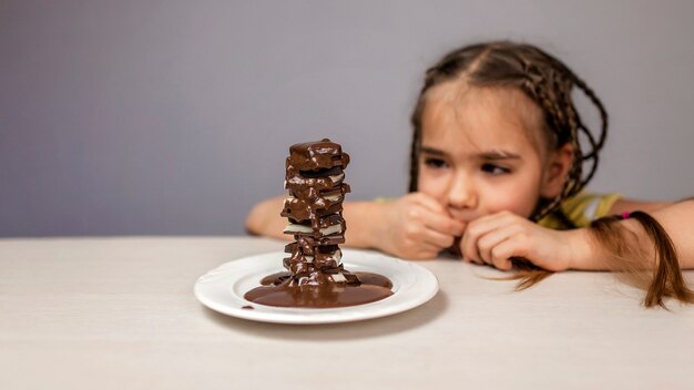 Menina servindo chocolate quente líquido em uma pilha de diferentes pedaços de chocolate