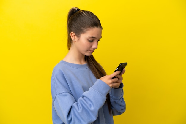 Menina sobre fundo amarelo isolado enviando uma mensagem ou e-mail com o celular