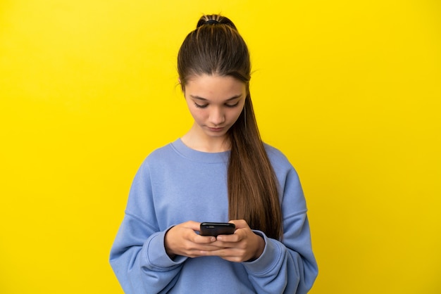 Menina sobre fundo amarelo isolado usando telefone celular
