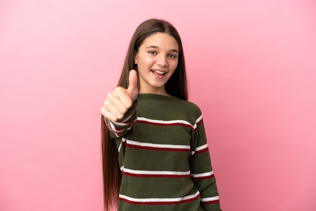 Menina sobre fundo rosa isolado com polegar para cima porque algo bom aconteceu