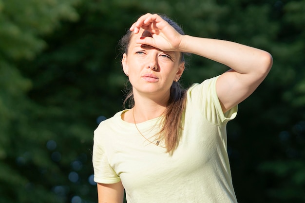 Menina sofrendo de dor, calor, mulher com insolação. tendo uma insolação no clima quente de verão. sol perigoso, garota sob o sol. dor de cabeça, me sentindo mal. pessoa segura a mão na cabeça. coronavírus