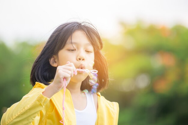 Menina, soprando bolhas de sabão no parque