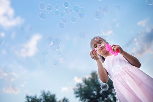 Foto menina soprando bolhas de sabão no parque