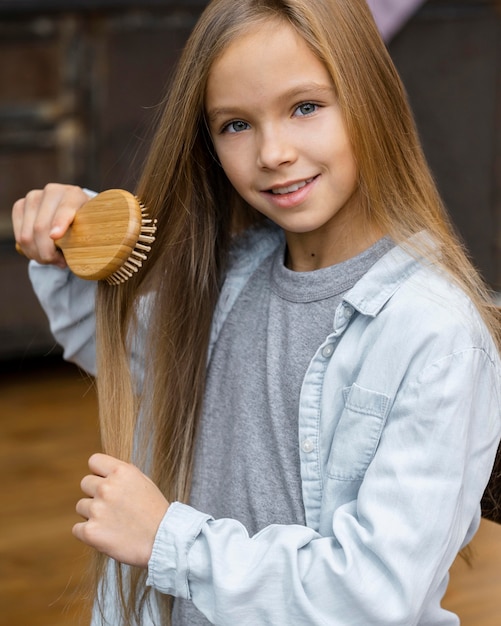 Foto menina sorridente a escovar o cabelo