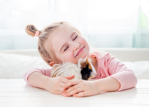 Menina sorridente, abraçando a cobaia