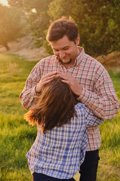 Foto menina sorridente, abraçando o pai lá fora