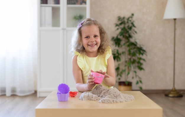 Menina sorridente bonitinha brincando com areia cinética