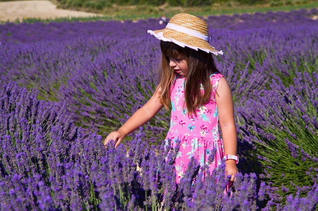 Menina sorridente cheirando flores em um campo de lavanda