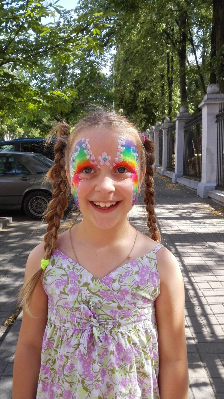 Foto menina sorridente com a cara pintada de pé na calçada