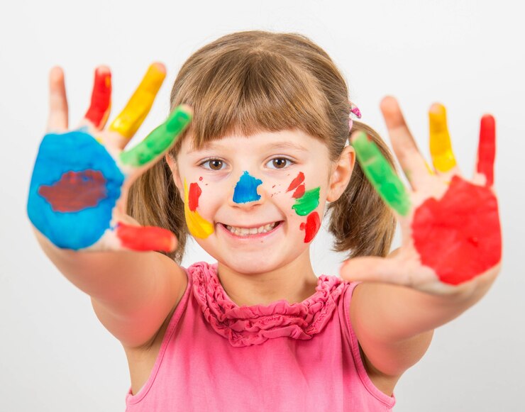 Menina sorridente com as mãos pintadas com tintas coloridas