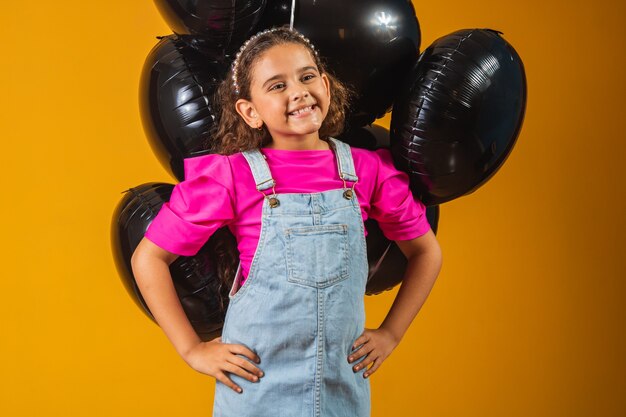 Menina sorridente com balões pretos na sexta-feira negra. festival de baixo preço