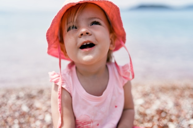 Menina sorridente com chapéu-panamá na praia retrato