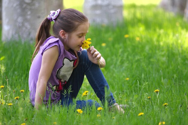 Menina sorridente com dente de leão em uma grama em um parque