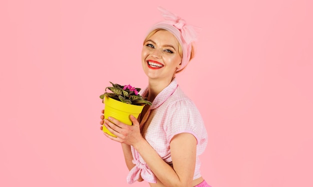 Menina sorridente com flor violeta africana desabrochando saintpaulia em mulher de maconha cultivando flores