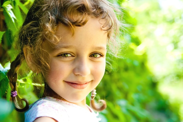 Menina sorridente com folhas verdes ao ar livre