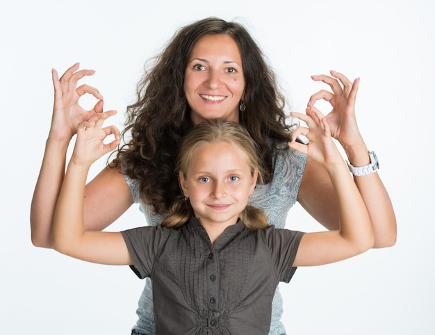 Menina sorridente com mãe mostrando sinal de ok