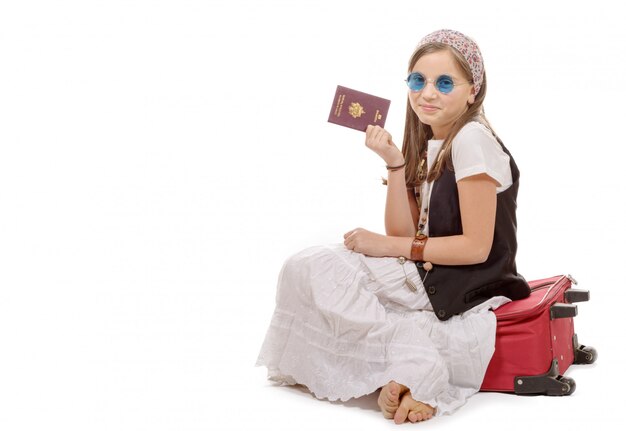 Menina sorridente com mala de viagem, passaporte isolado sobre o branco