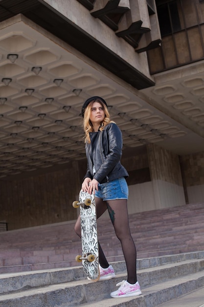 Menina sorridente com o skate subindo as escadas