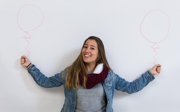 Menina sorridente com os braços abertos finge segurando dois balões desenhados em fundo branco