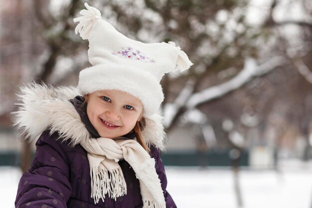 Menina sorridente com roupas de inverno Atividade de inverno ao ar livre Criança com roupas de inverno brinca com admiração