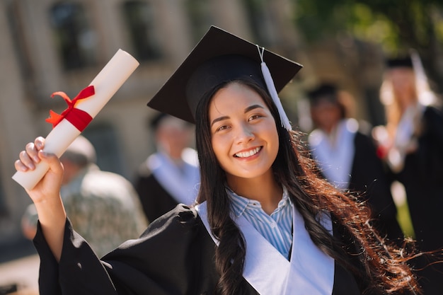 Menina sorridente com seu diploma e orgulhosa de seu mestrado