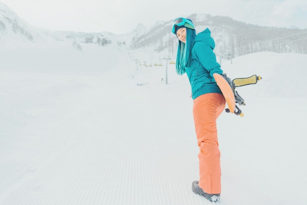 Menina sorridente com snowboard na estação de esqui