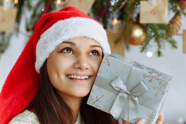 menina sorridente com um chapéu de Natal e uma caixa de presente closeup