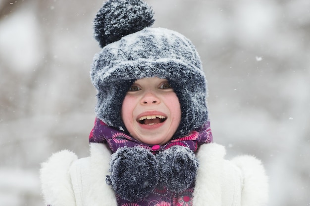 Menina sorridente de casaco rosa na floresta de inverno