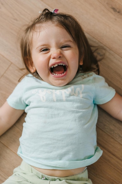 Foto menina sorridente deitada de costas olhando para a câmera e sorrindo desenvolvimento do bebê