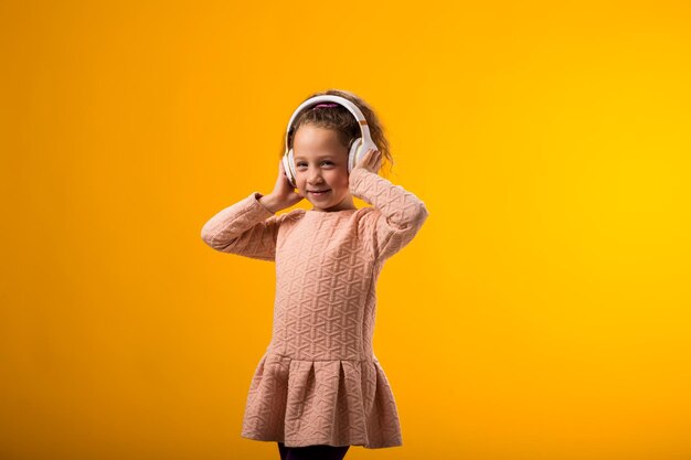 Menina sorridente desfrutando de música em fones de ouvido em fundo amarelo conceito de estilo de vida e lazer