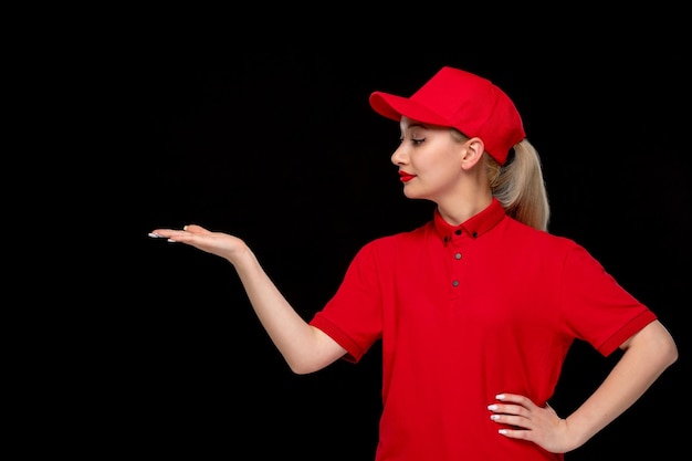 Menina sorridente do dia da camisa vermelha com acenando as mãos em um boné vermelho vestindo camisa e batom brilhante