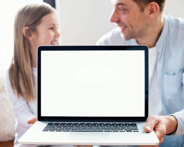 Menina sorridente e pai segurando laptop