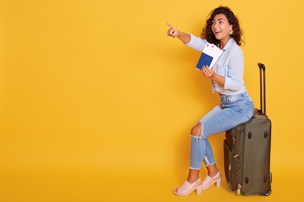 Menina sorridente em roupas elegantes, isolado sobre fundo rosa. Passageiros que viajam para o exterior,