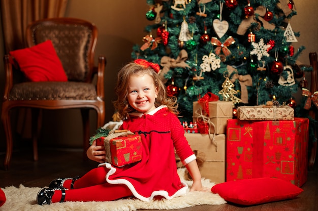 Menina sorridente entre presentes de Natal